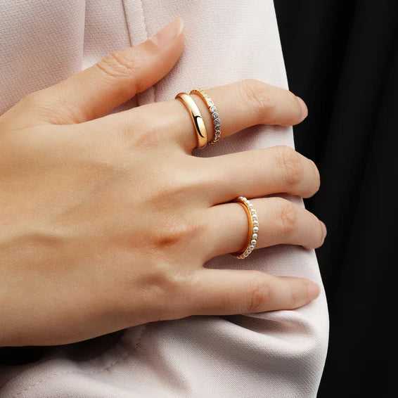 Hand wearing two gold rings on a light fabric background
