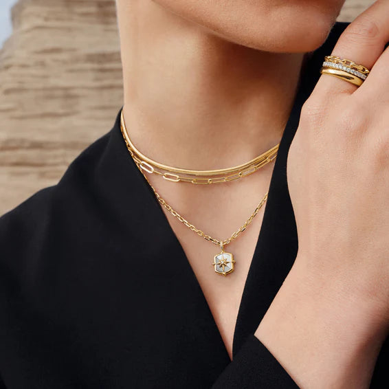 Close-up of a person wearing gold jewelry including a necklace and bracelets.