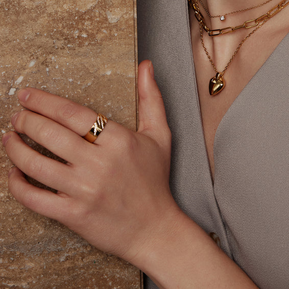Hand wearing a gold ring with a textured surface background