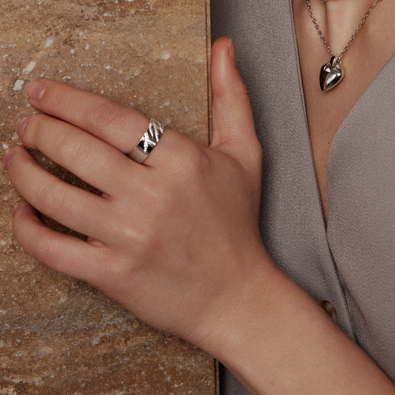 Hand wearing a silver ring on a stone surface