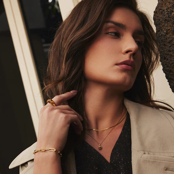 Woman wearing gold jewelry with a neutral background