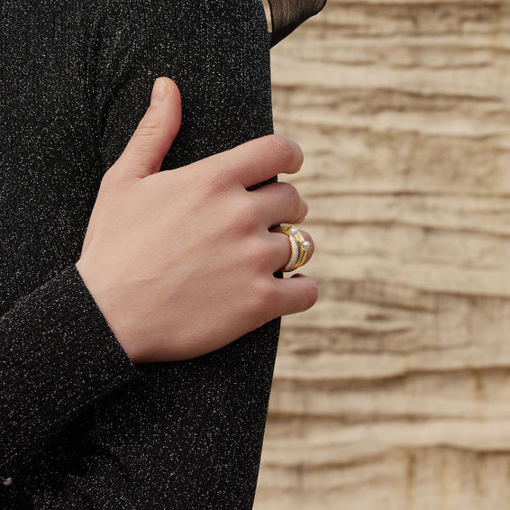 Hand wearing a gold ring with a textured background