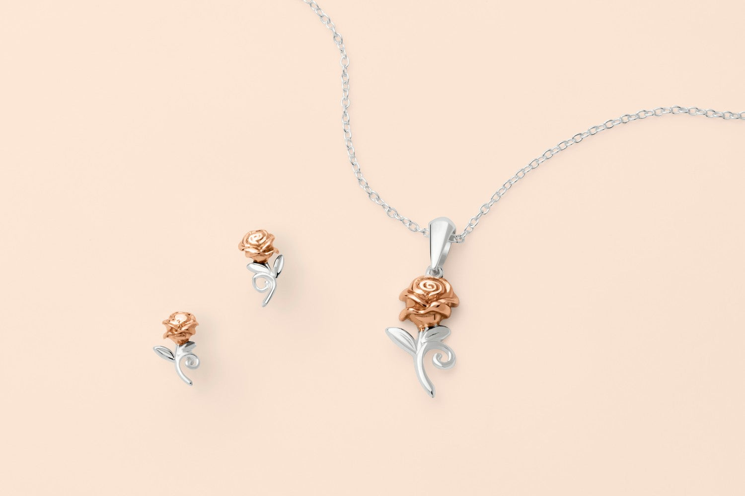 Jewelry set with rose-shaped pendant and earrings on a beige background