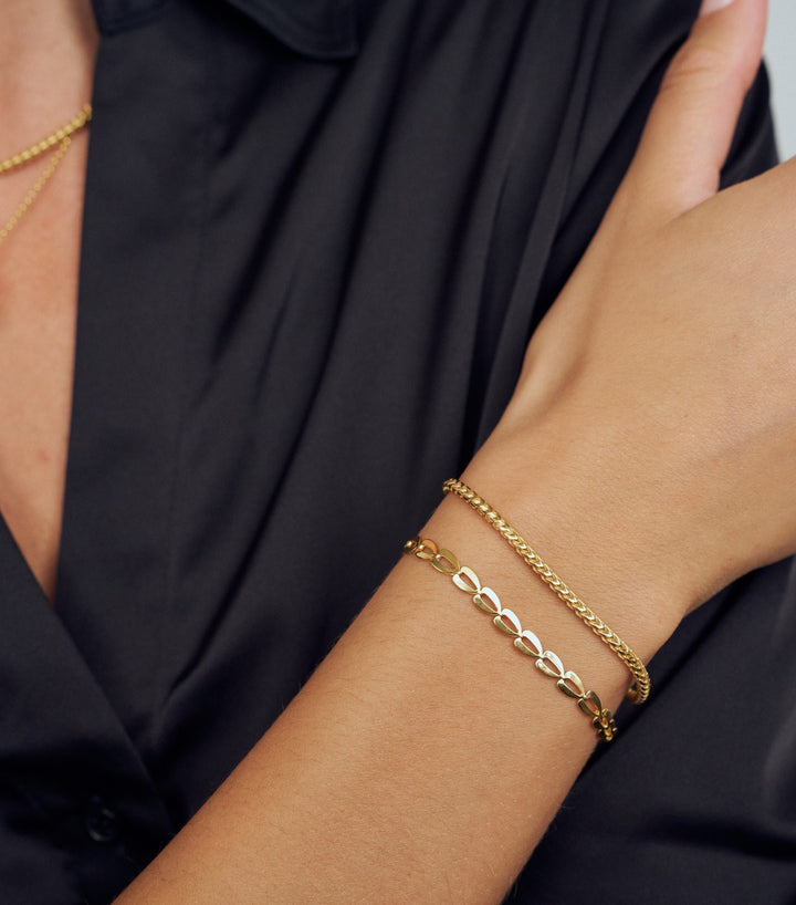 Gold bracelet on a person's wrist with a black background