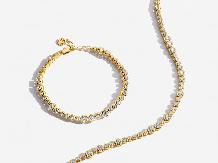 Gold bracelet and necklace set on a white background