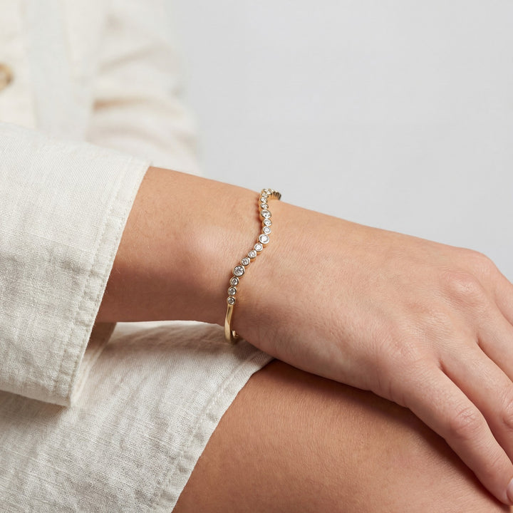 Gold bracelet on a wrist with a neutral background