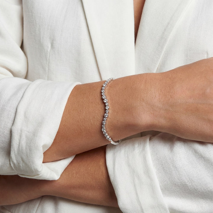 Silver bracelet on a person's wrist with a white background