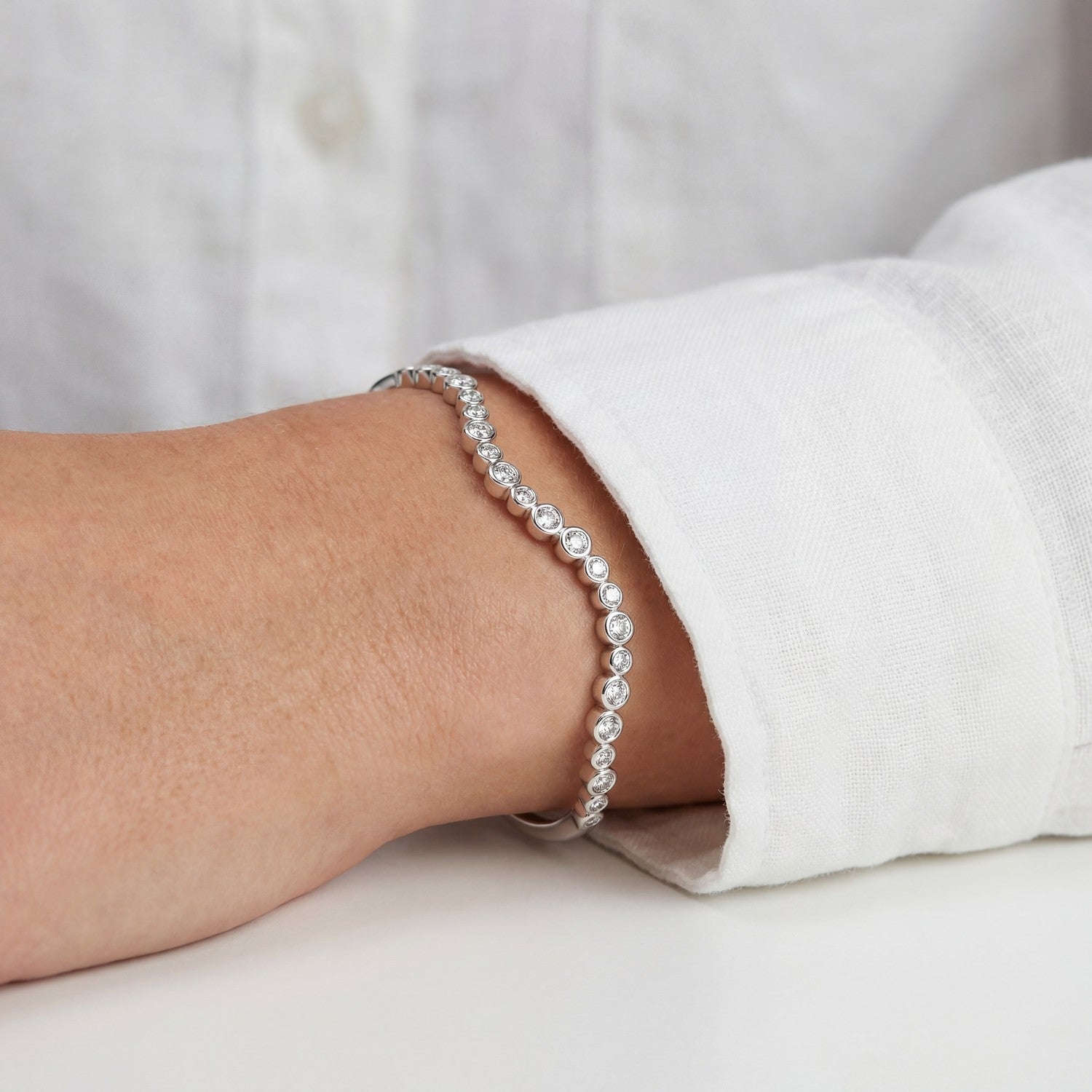 Silver bracelet on a wrist with a white shirt background