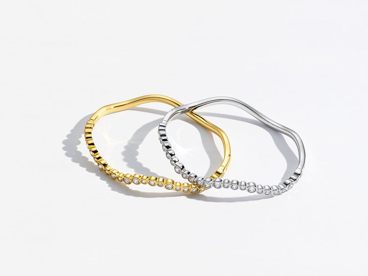 Two hoop earrings, one gold and one silver, on a light gray background