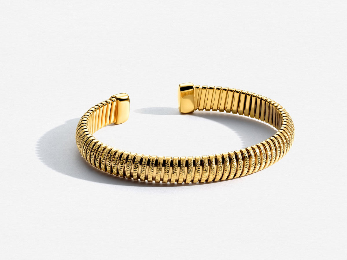 Gold bracelet with ribbed design on a white background