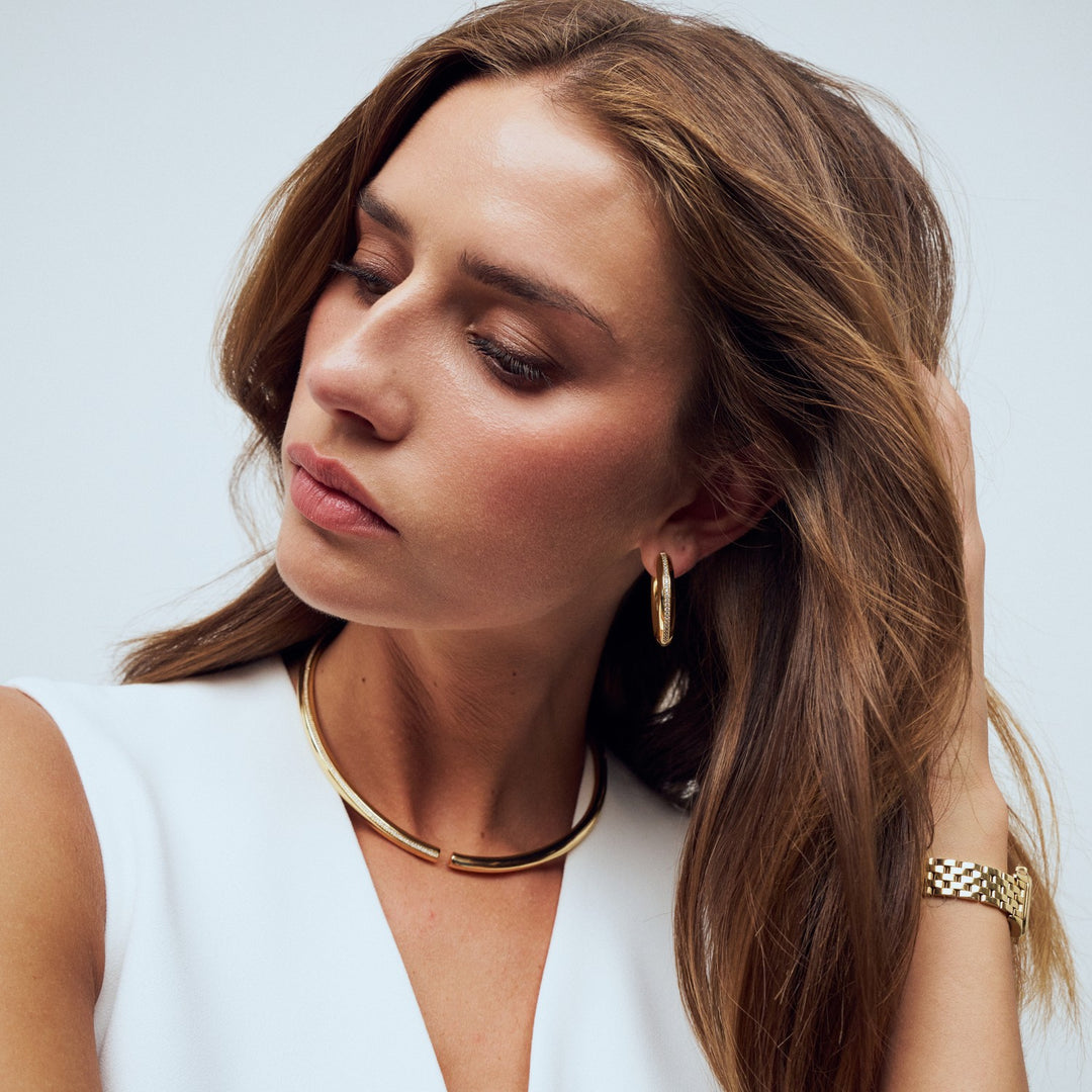 Woman wearing gold jewelry against a plain background