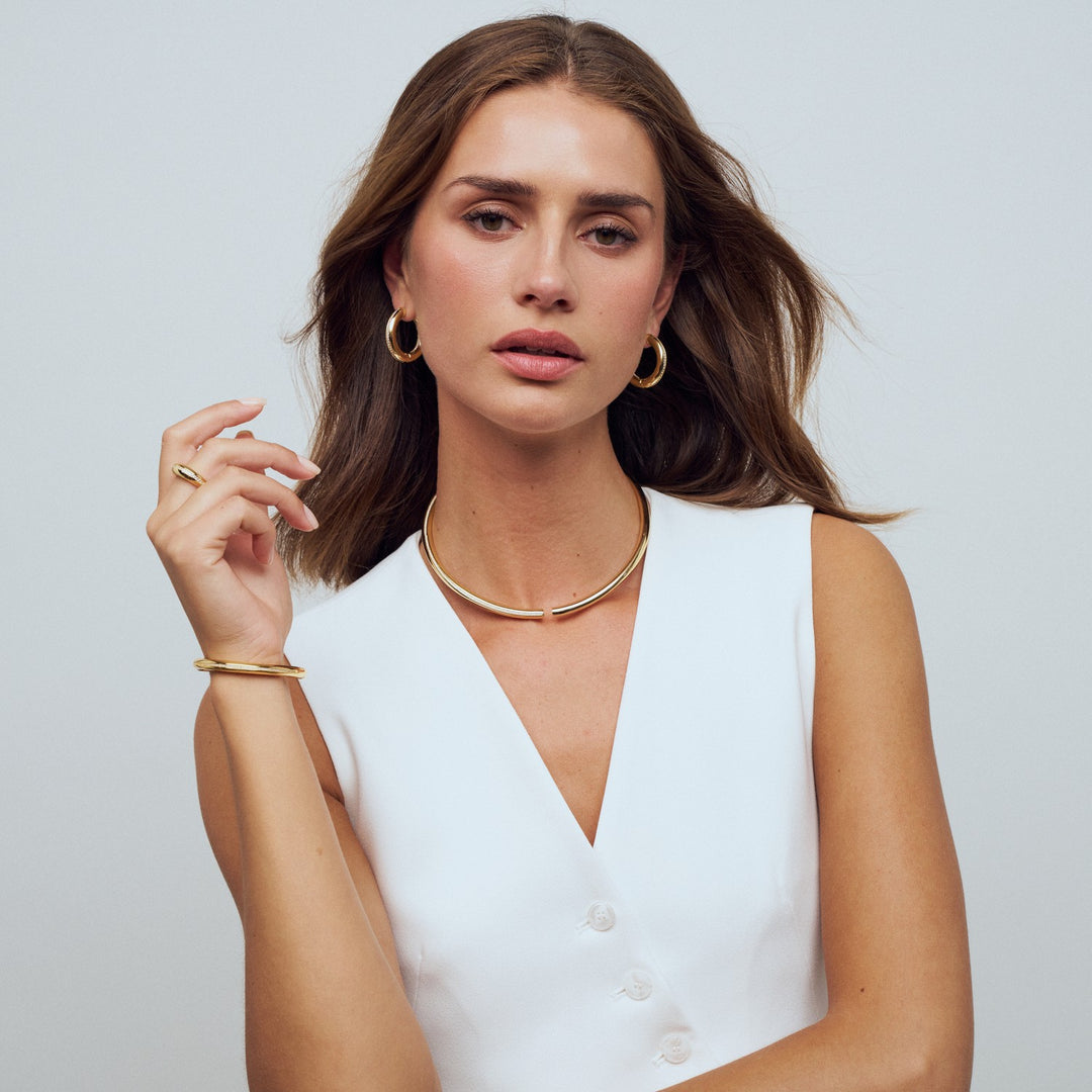Woman wearing gold jewelry against a plain background