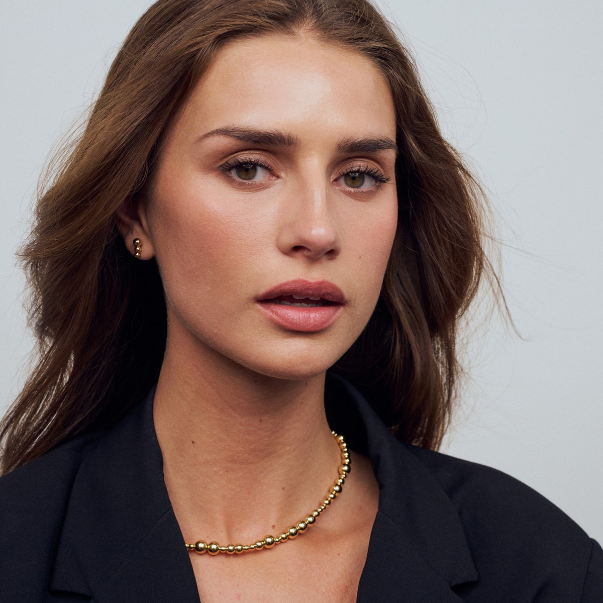 Woman wearing a gold necklace against a plain background