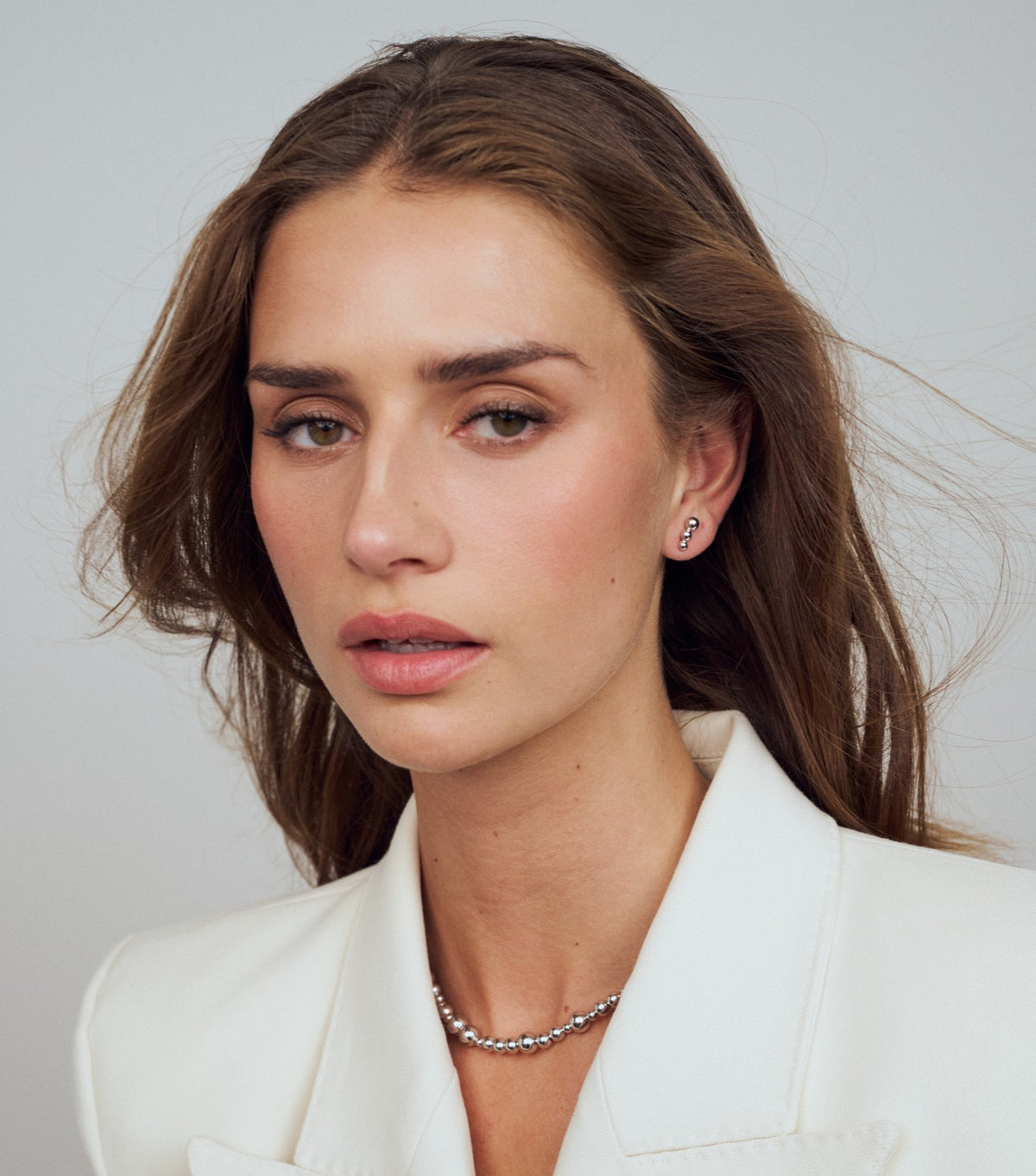 Woman wearing a white blazer with a plain background