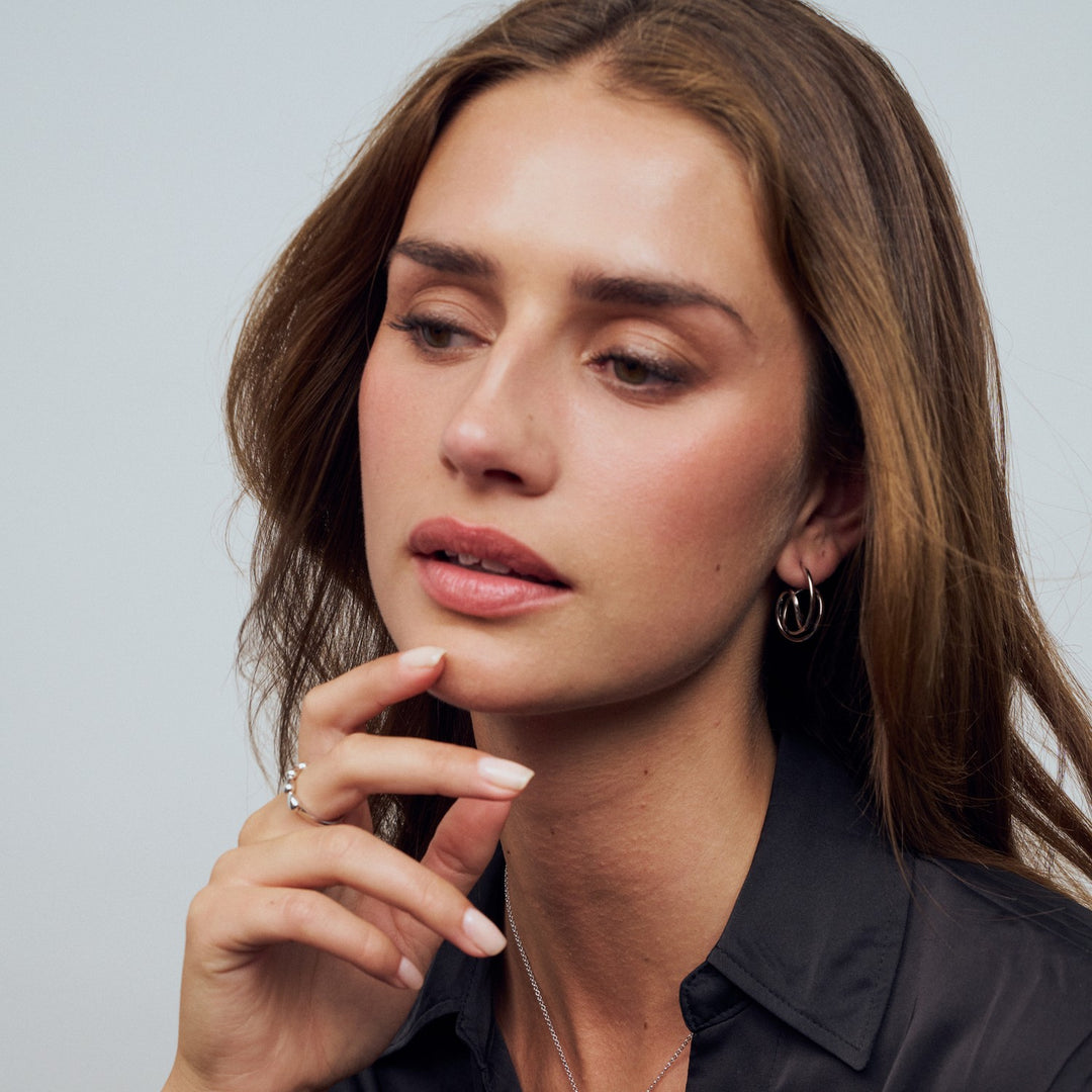 Woman with hand near her face against a neutral background