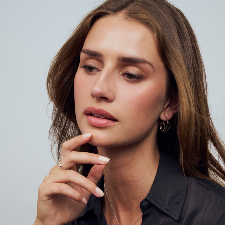 Woman with hand near her face against a neutral background