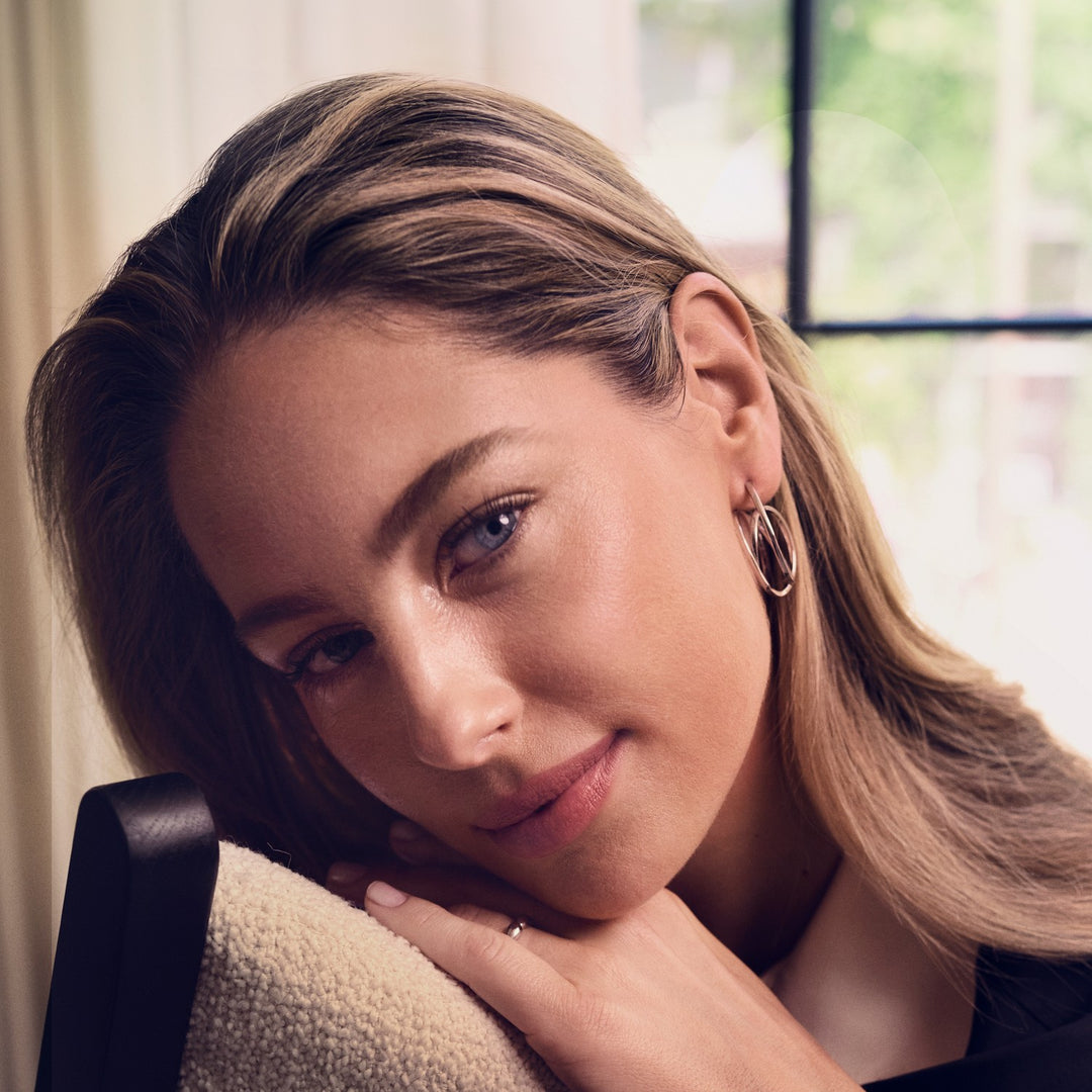 Woman with blonde hair and hoop earrings sitting indoors.