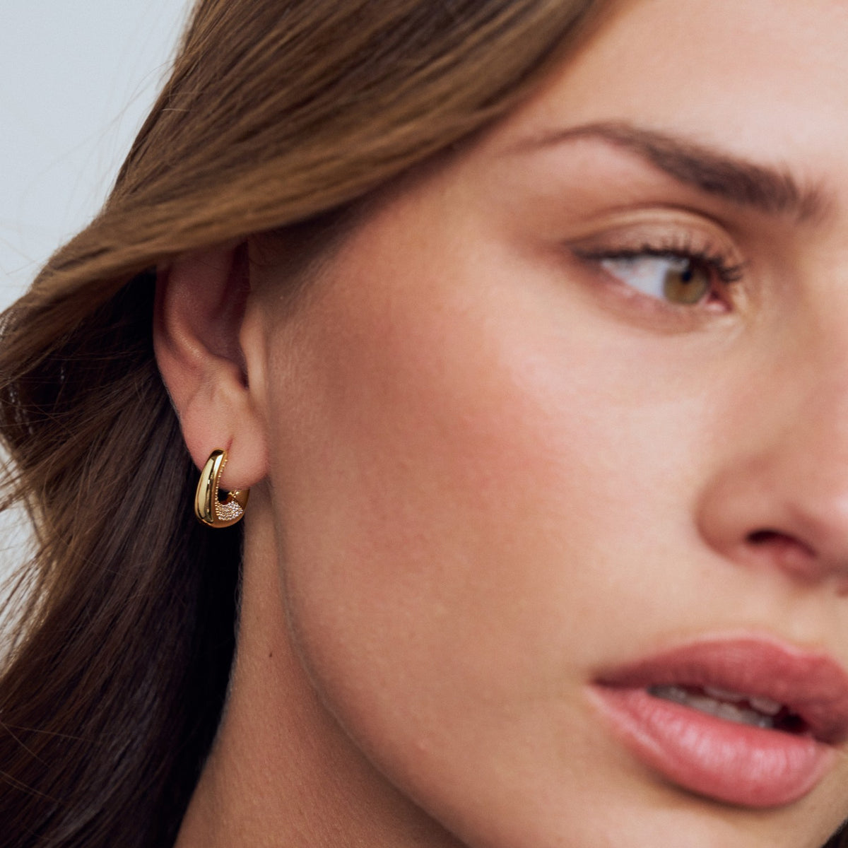 Close-up of a woman wearing a gold hoop earring.