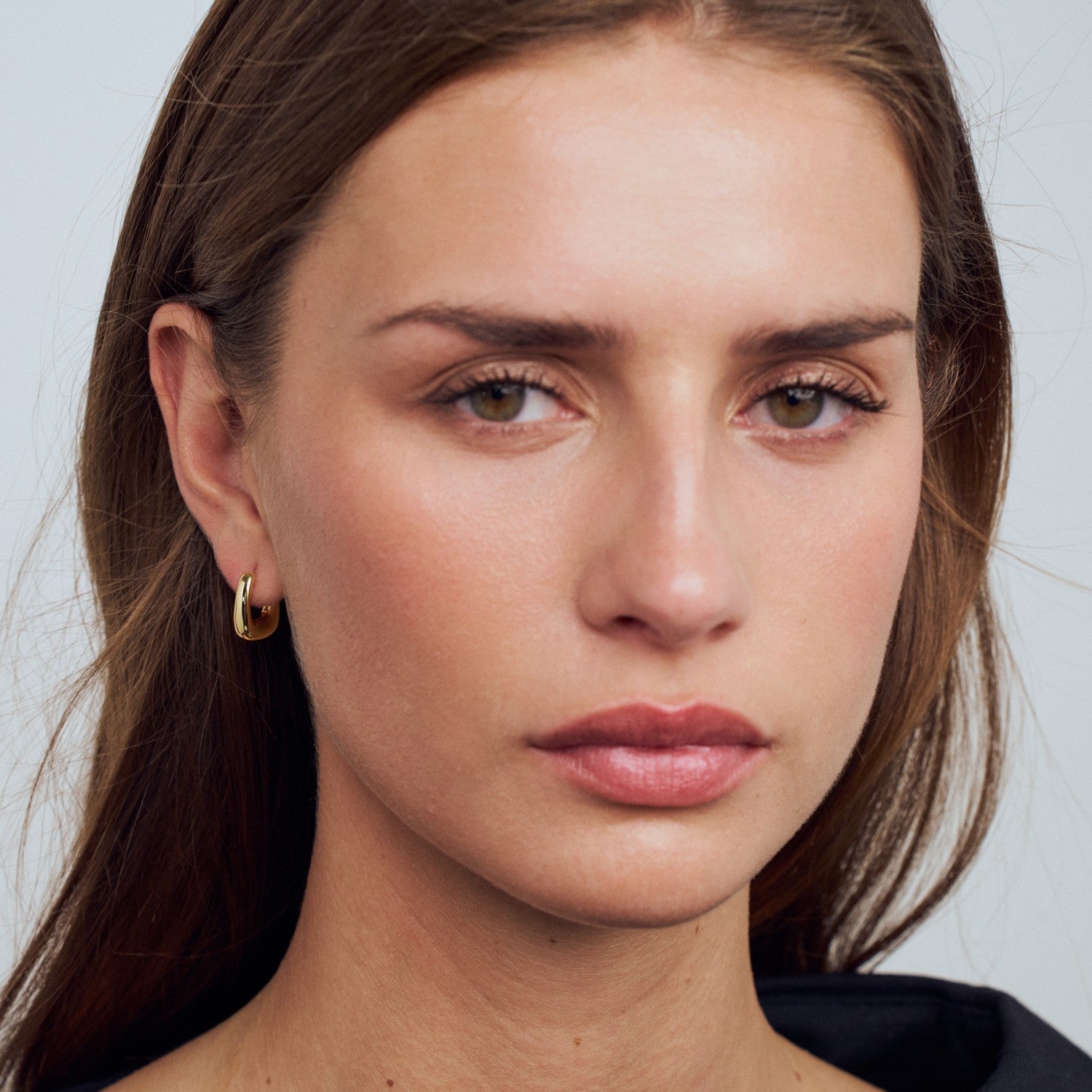 Close-up of a woman's face with a neutral expression on a plain background