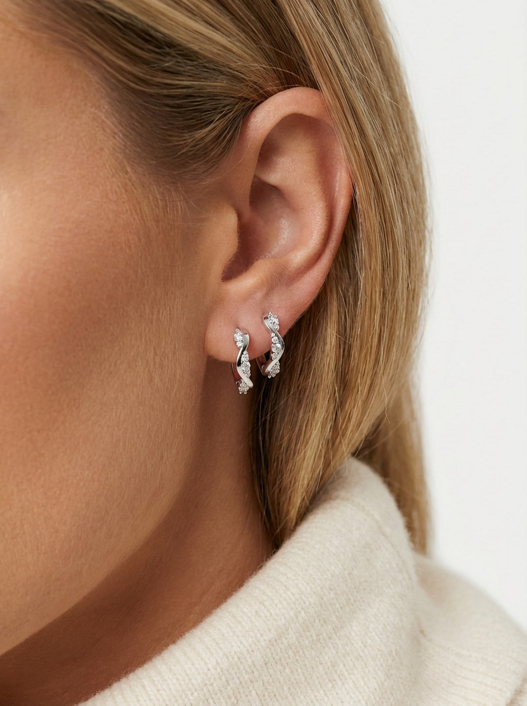 Close-up of an ear wearing a silver earring with a blurred background