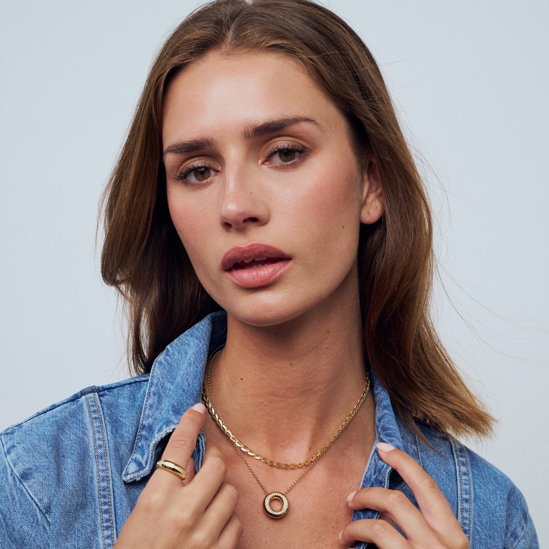 Woman wearing a gold necklace with a plain background