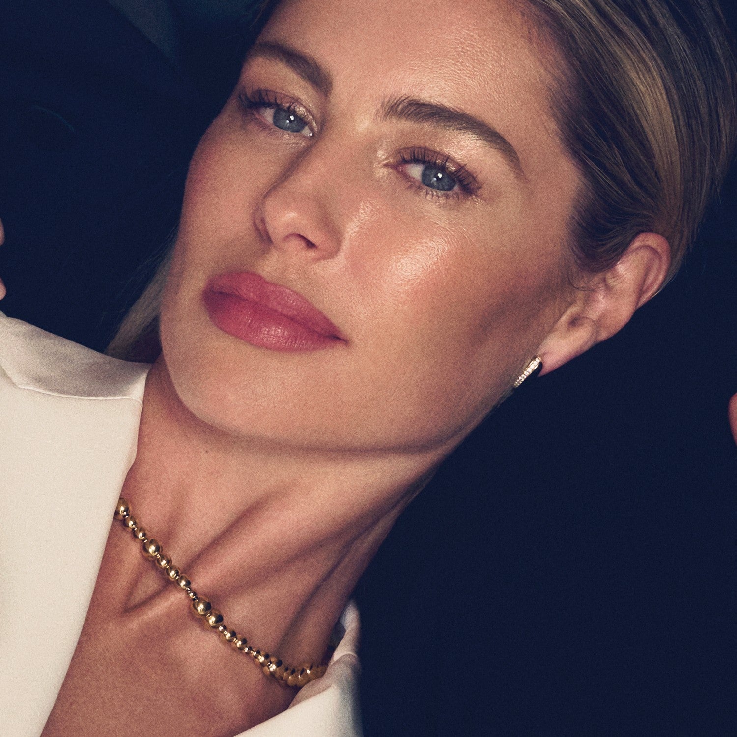 Close-up of a woman wearing a necklace with a dark background