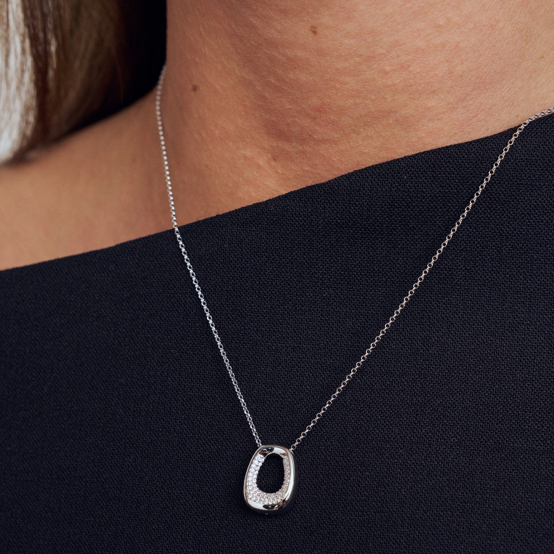 Silver necklace with a pendant on a person wearing a black top