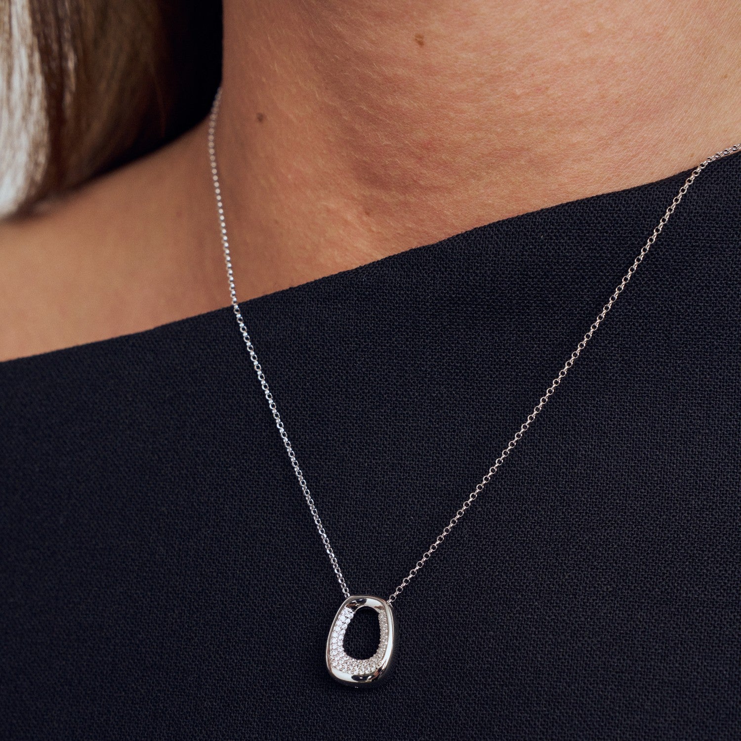 Silver necklace with a pendant on a person wearing a black top