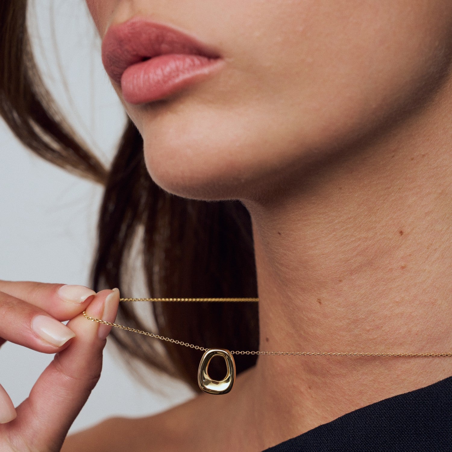 Close-up of a person wearing a gold necklace with a small pendant.