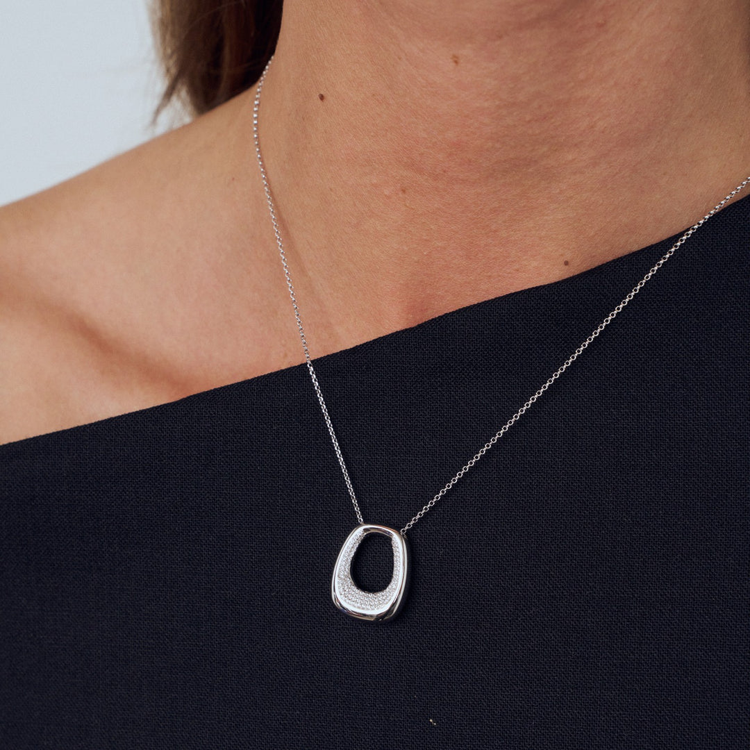 Silver necklace with a unique pendant on a person wearing a black top.