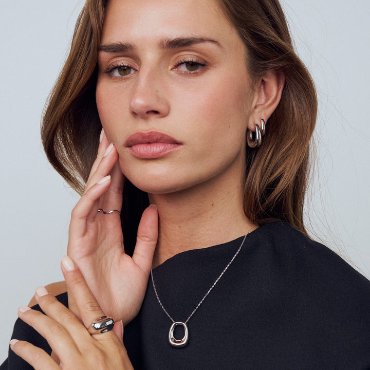 Woman wearing a necklace and earrings with a neutral background