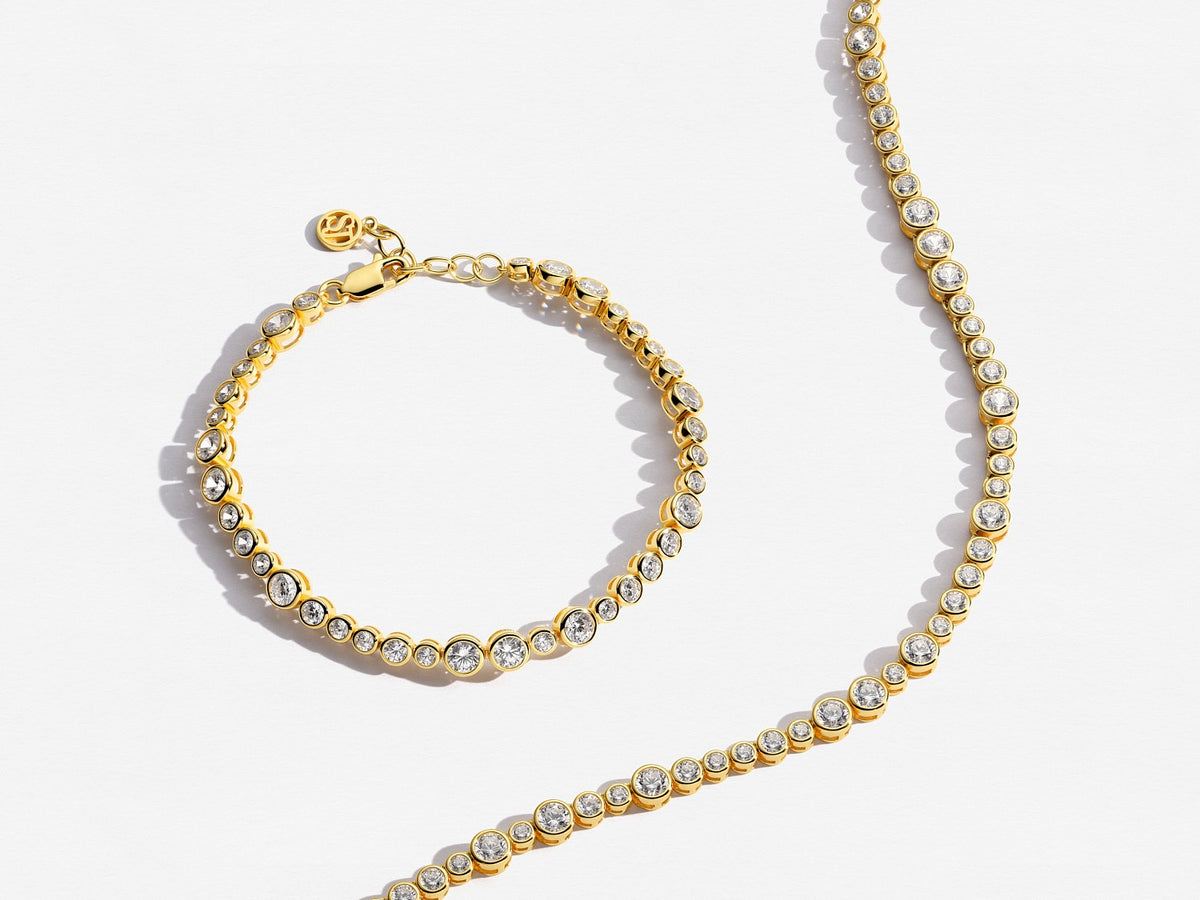 Gold bracelet and necklace set on a white background