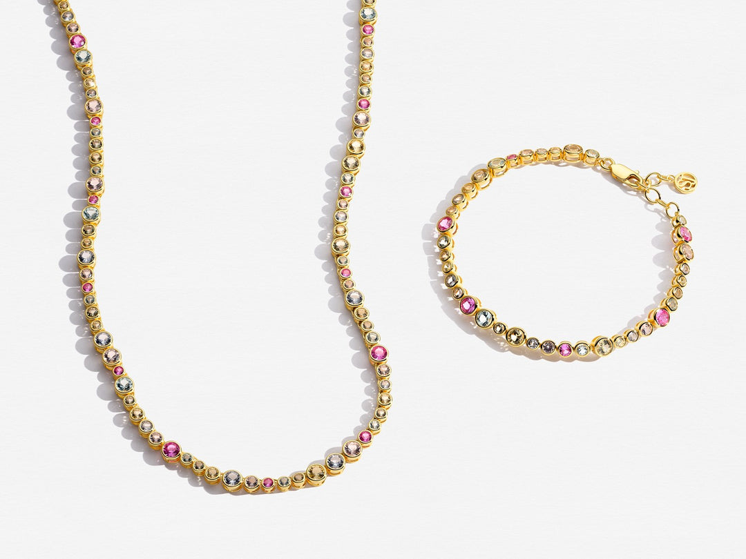 Gold necklace and bracelet with pink beads on a white background