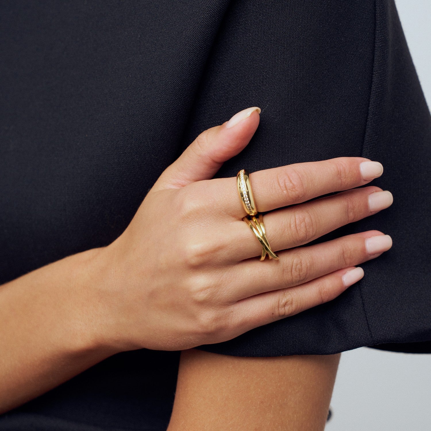 Hand wearing a gold ring on a dark background