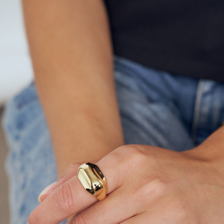 Gold ring on a person's finger with a blurred background