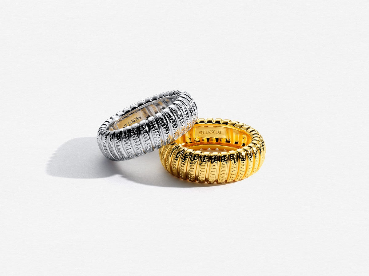 Two rings, one gold and one silver, on a white background