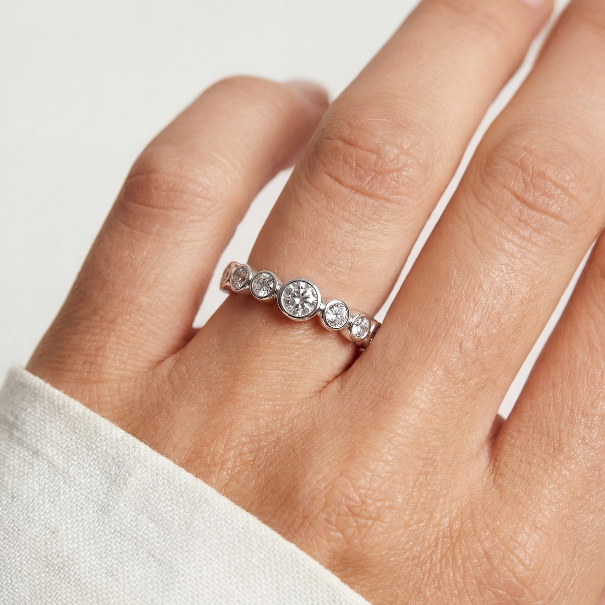 Close-up of a hand wearing a diamond ring on a light background