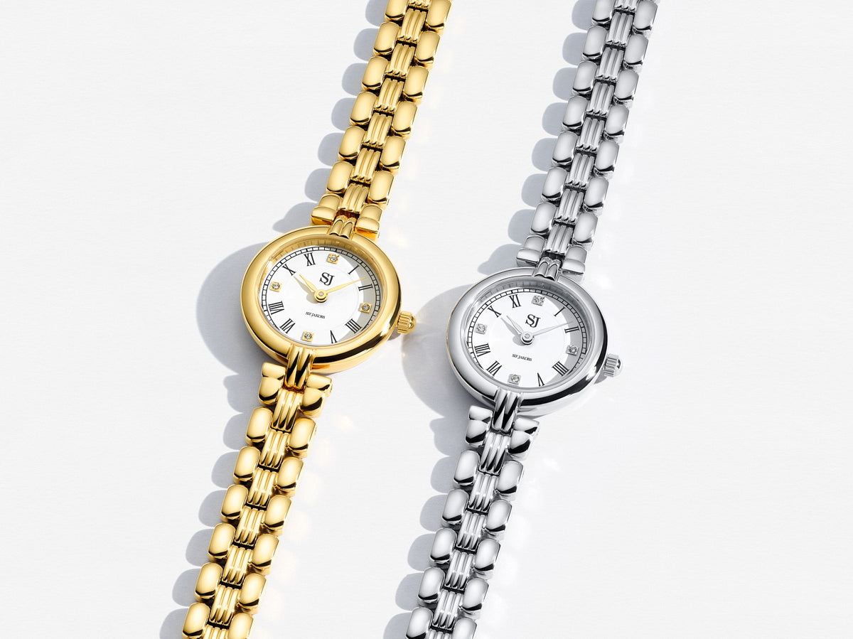 Two watches, one gold and one silver, on a light background