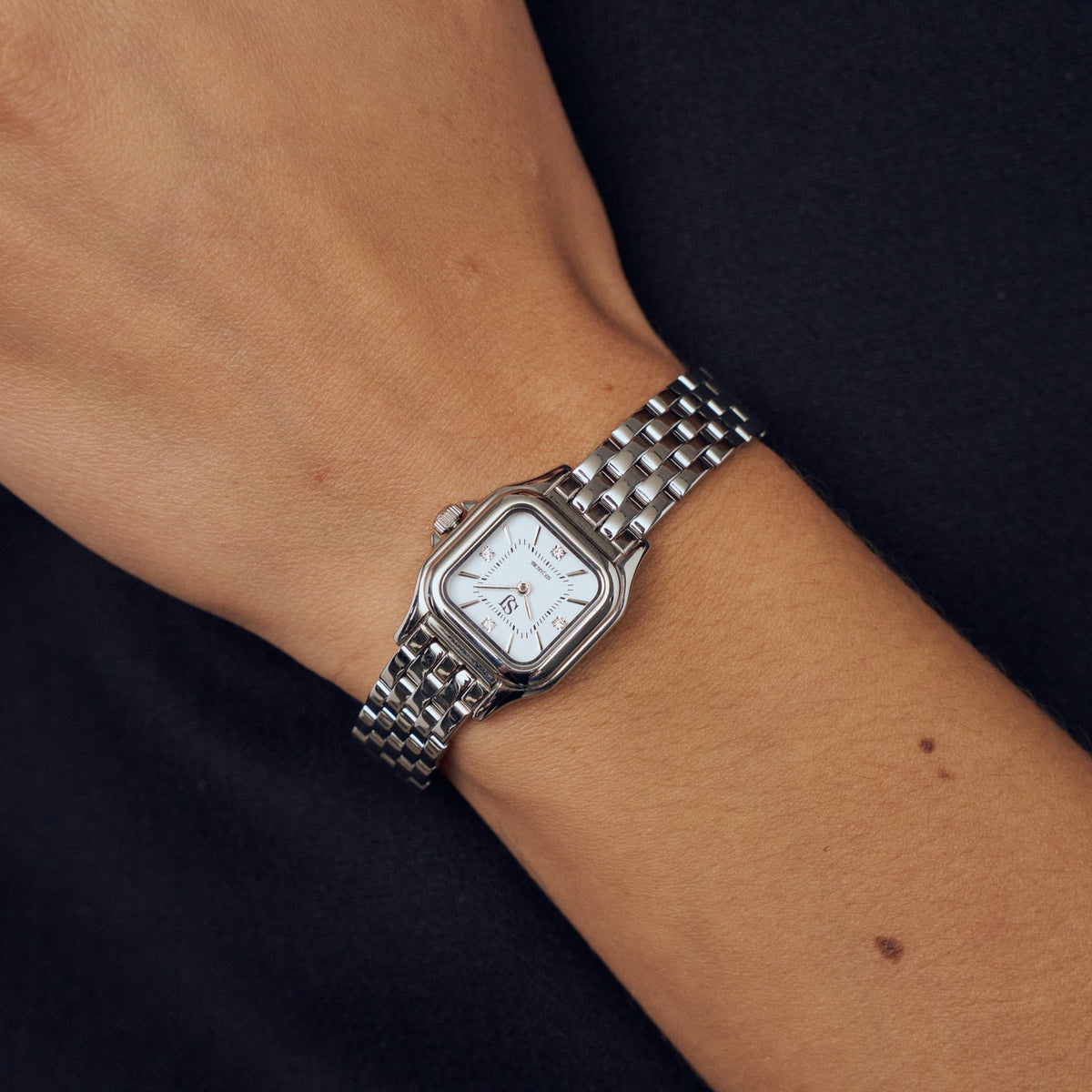 Silver watch on a wrist with a dark background