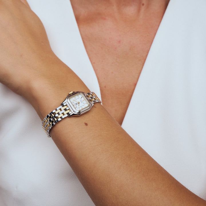 Silver watch on a wrist with a blurred white background