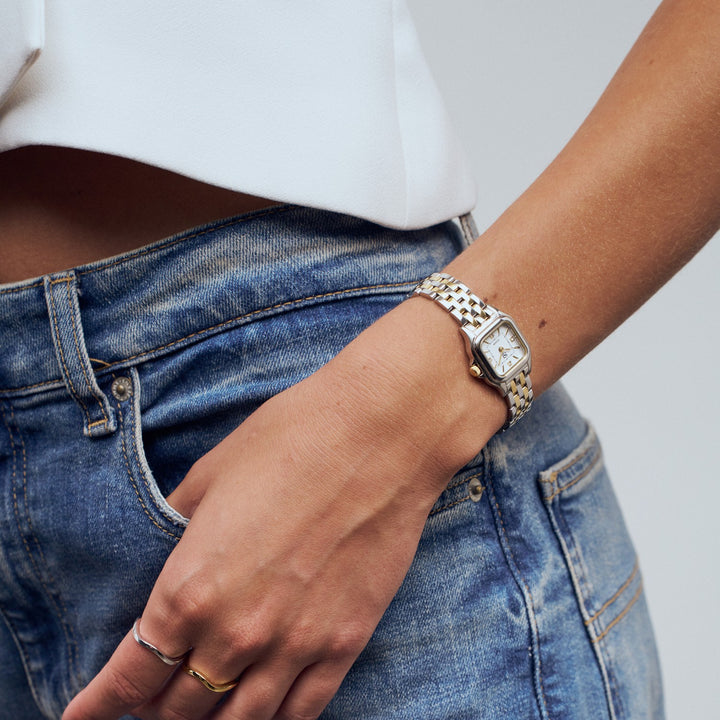Person wearing a gold watch on a plain background