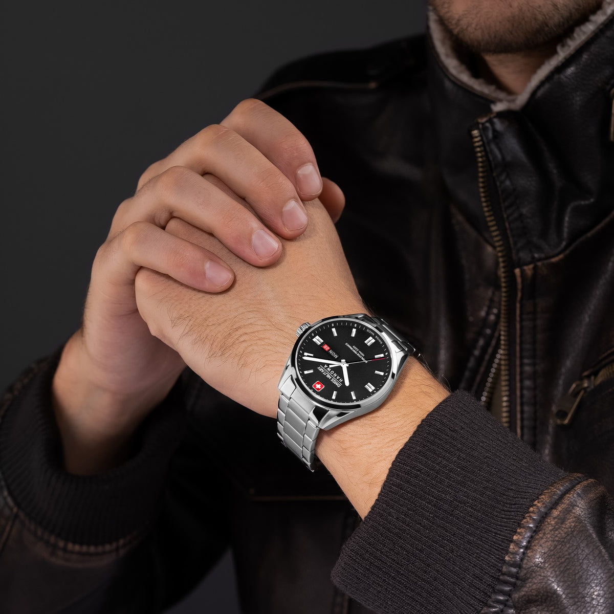 Person wearing a black watch with a silver strap on a dark background