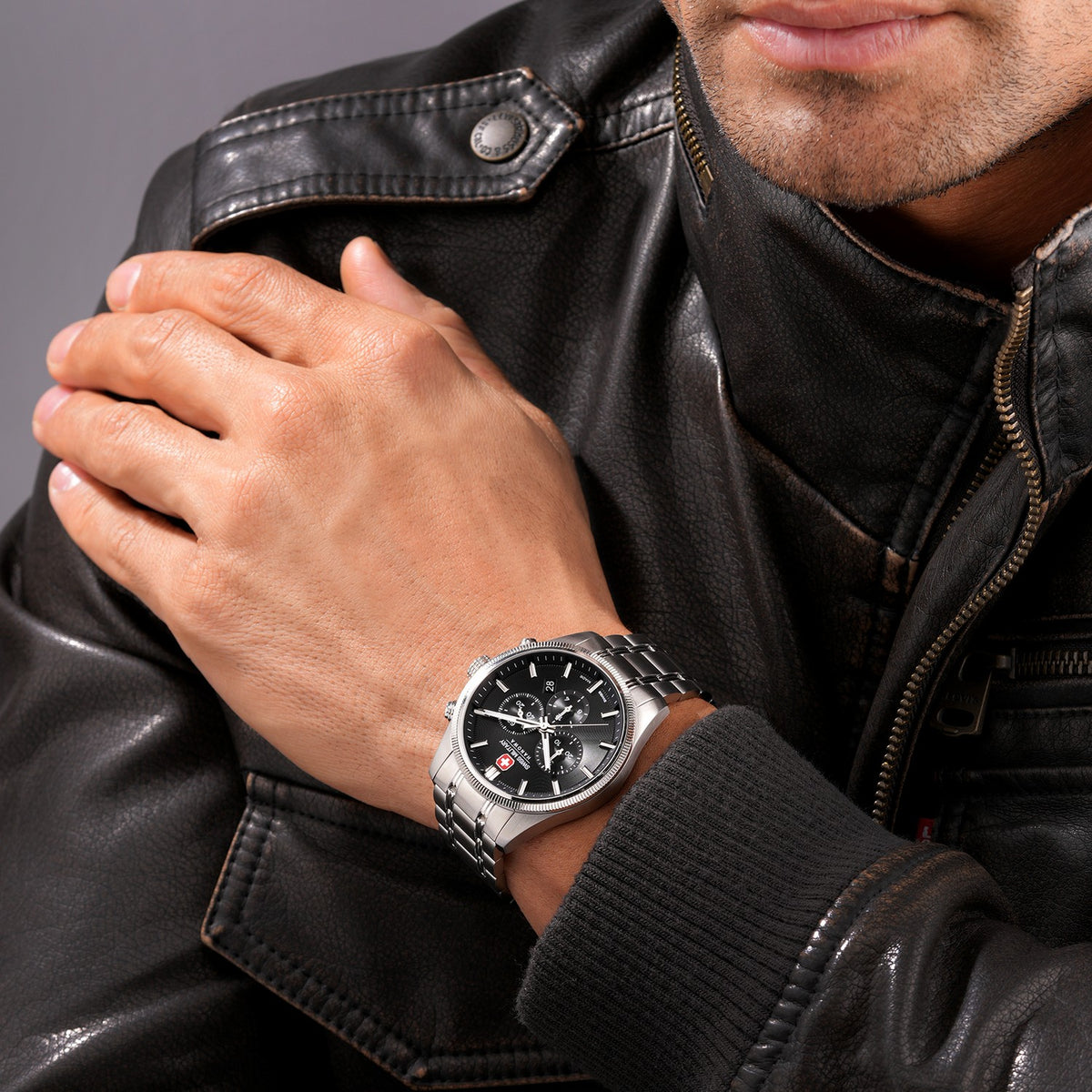 Man wearing a black leather jacket with a close-up of his wrist showing a silver watch.