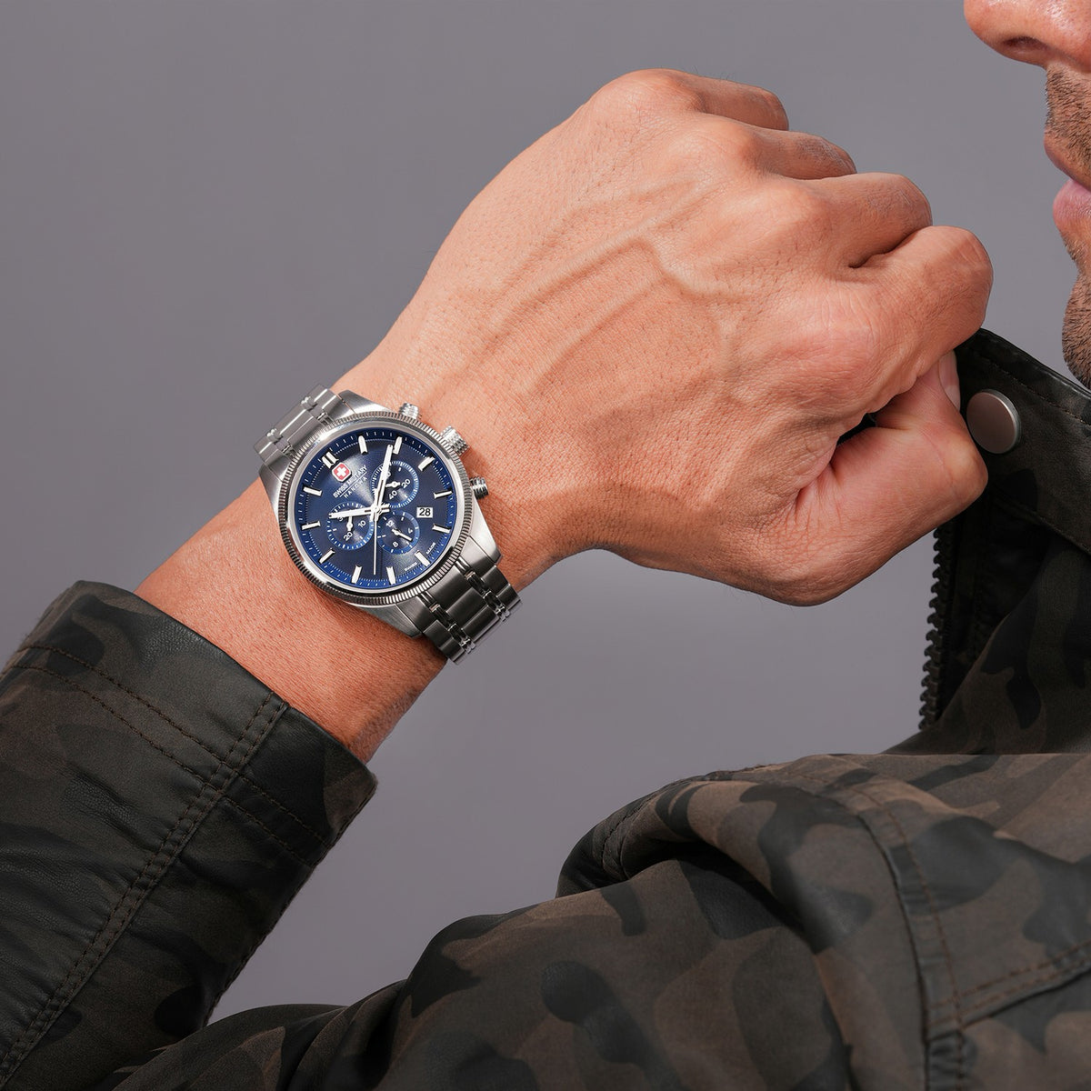 Close-up of a person wearing a watch with a blue face on a gray background