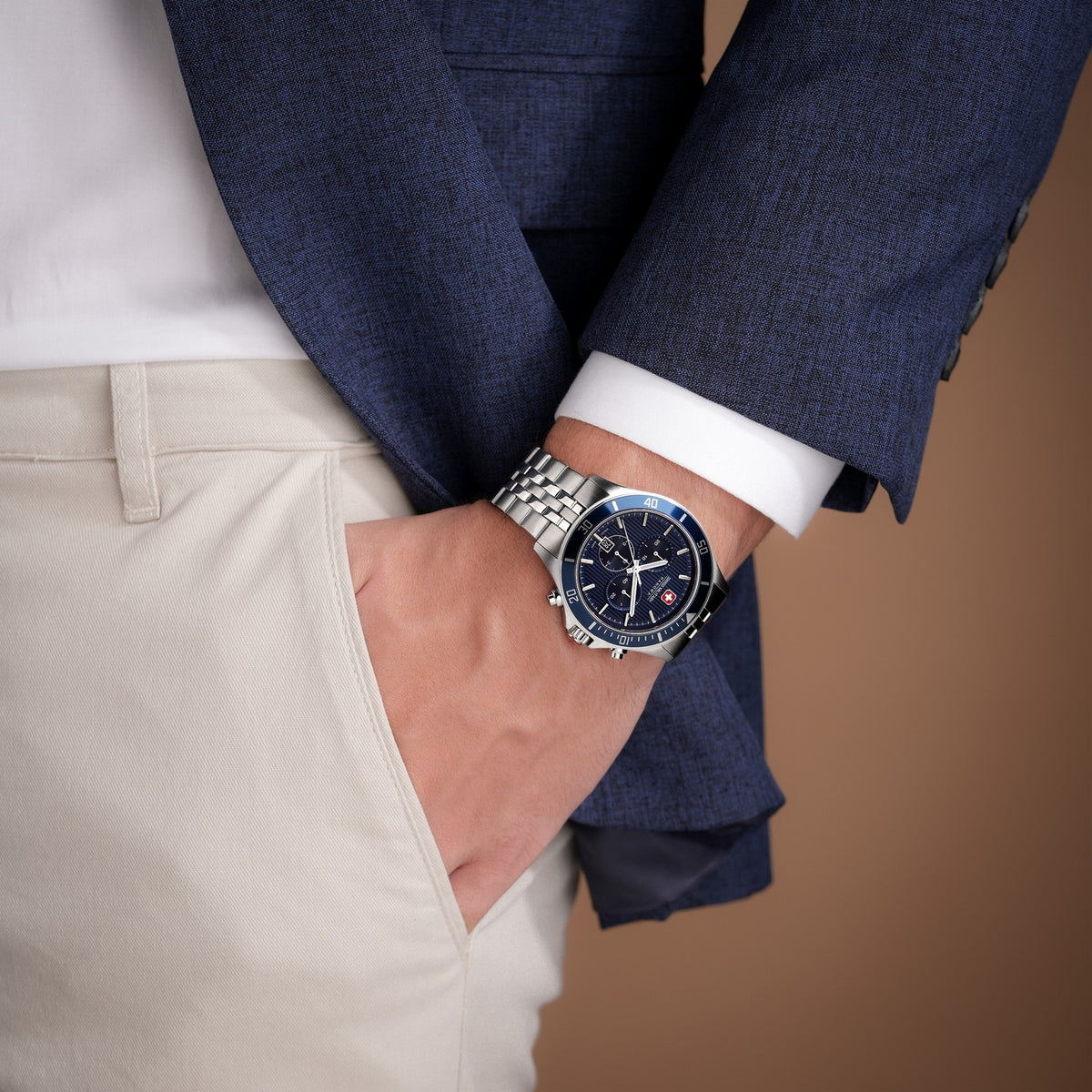 Person wearing a blue suit with a silver watch on a brown background