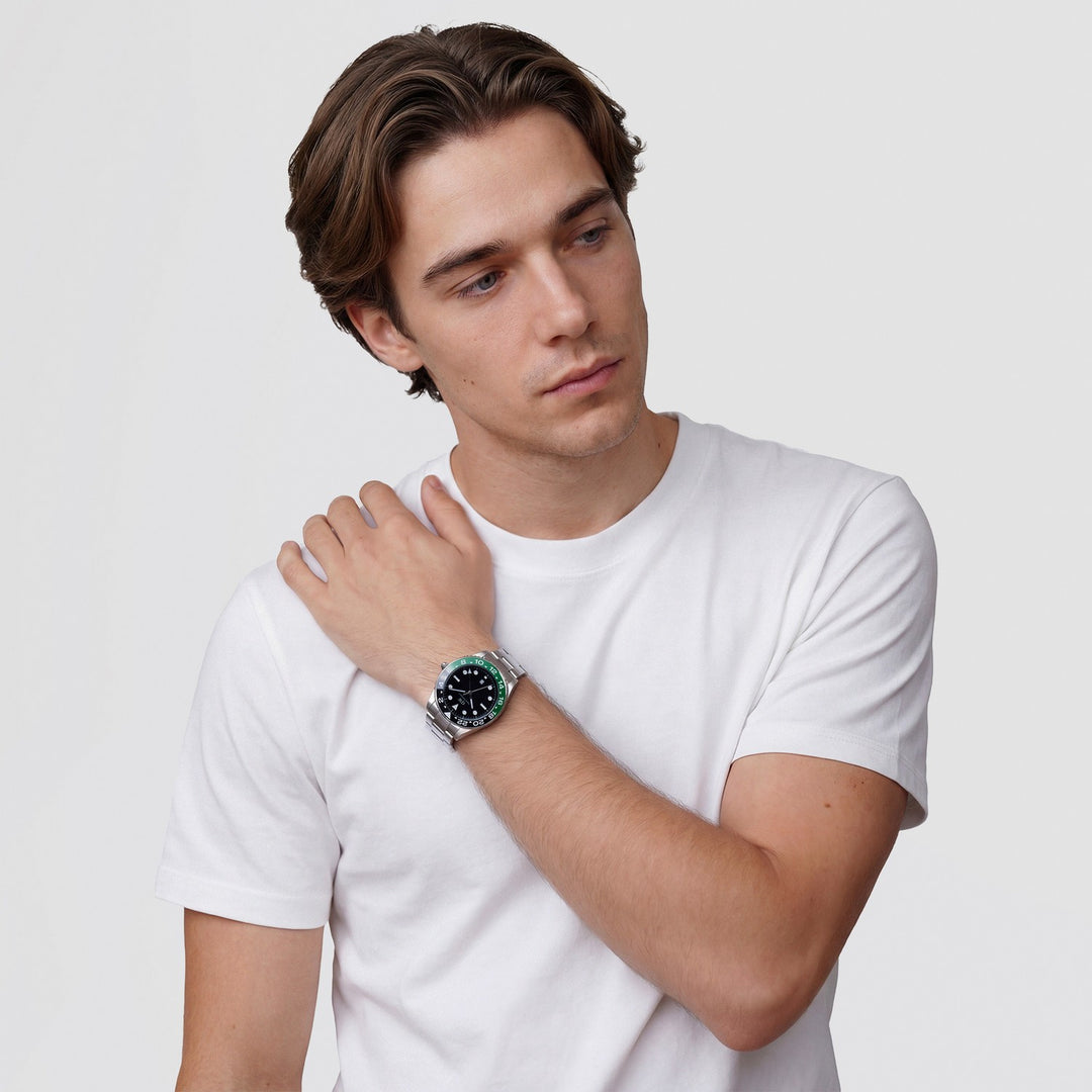 Man wearing a white t-shirt and a watch with a green face on a light gray background
