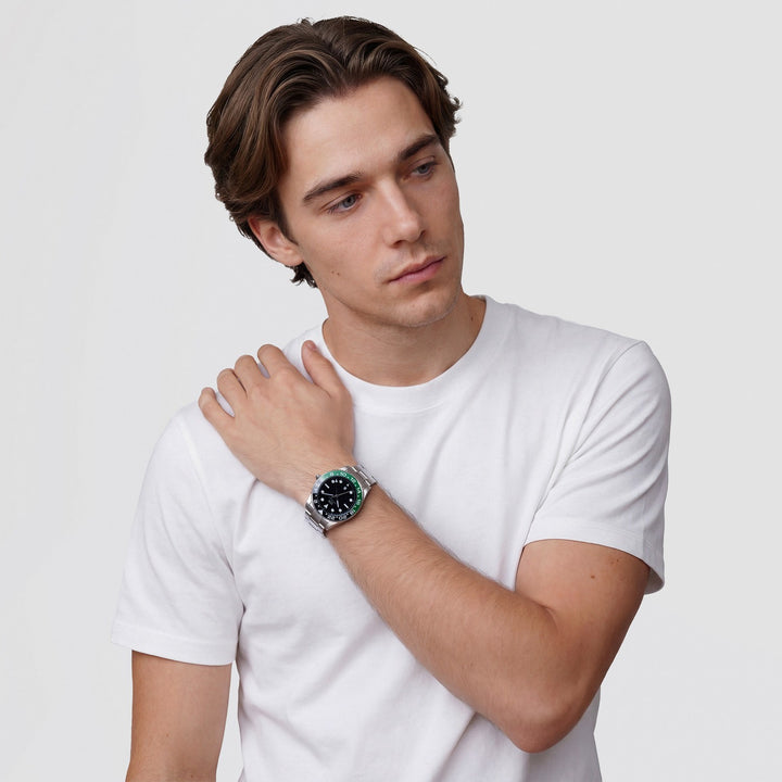 Man wearing a white t-shirt and a watch with a green face on a light gray background