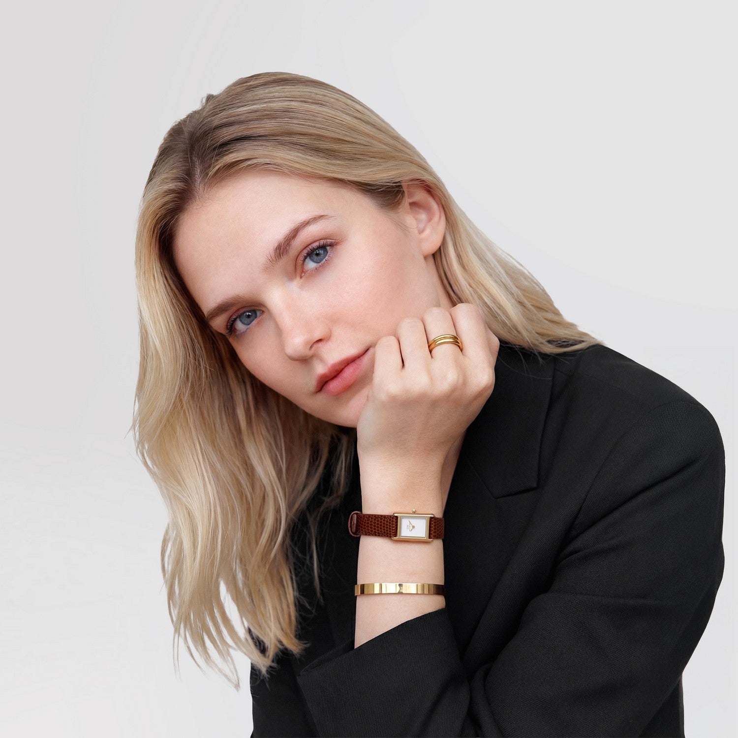 Woman wearing gold jewelry on a plain background