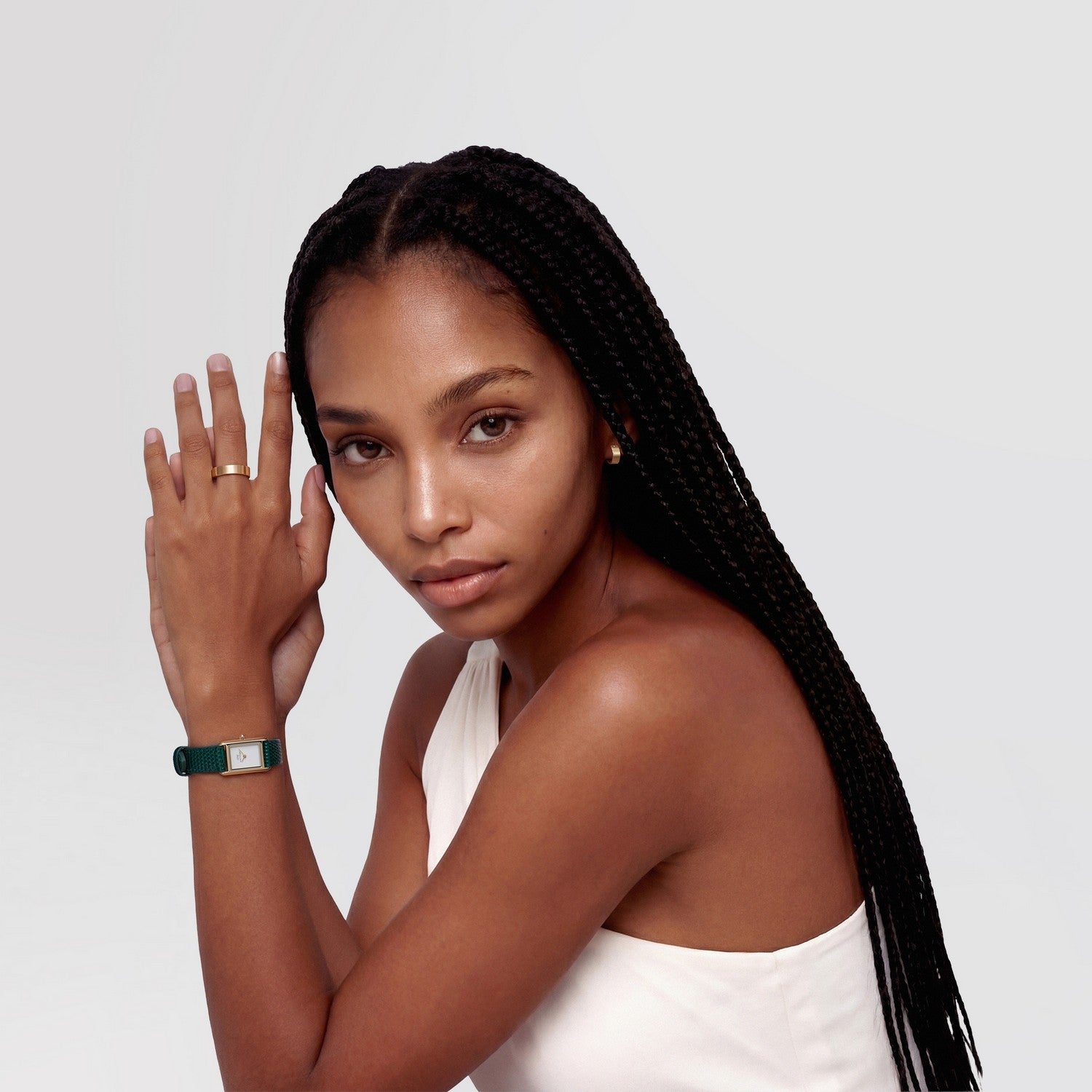 Woman with braided hair wearing a white top against a light gray background