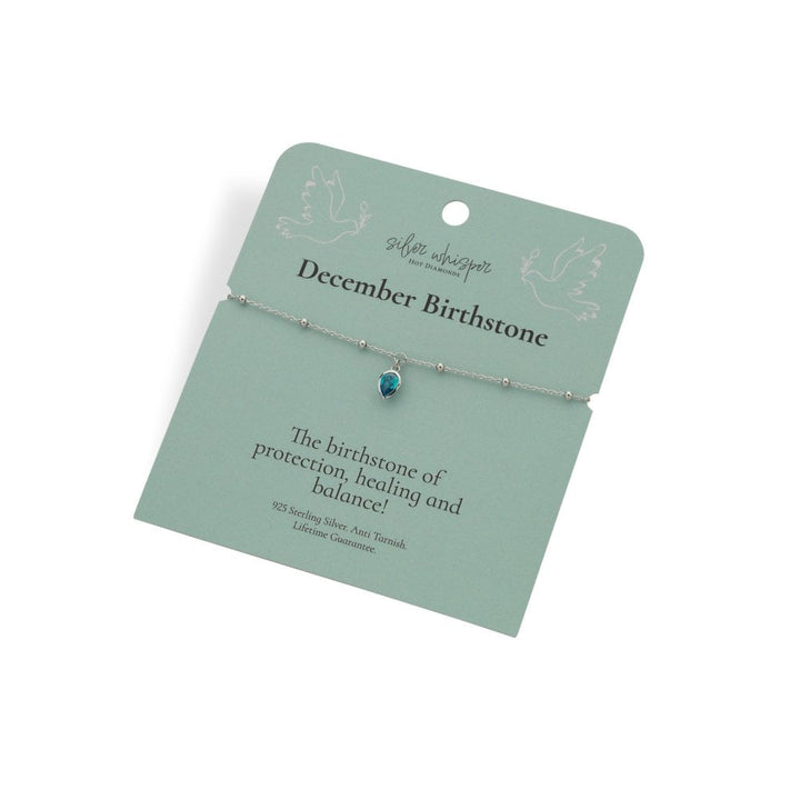 Bracelet with a blue gemstone on a green card with text about December birthstone